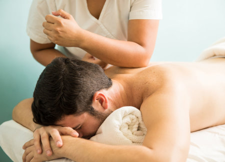 Man receiving a massage and massage therapist is using her elbow to work on tight muscles.